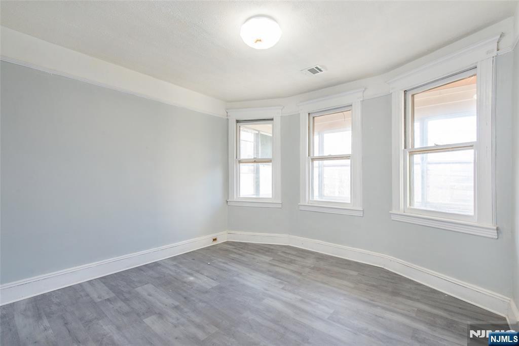 51 Maple Street Garfield, NJ 07026 - Photo 8 of 12 an empty room with wooden floor and windows
