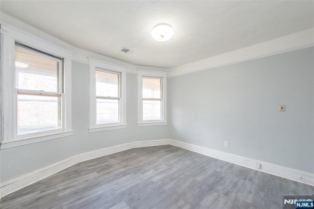 51 Maple Street Garfield, NJ 07026 - Photo 9 of 12 an empty room with wooden floor and windows