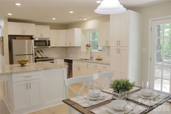 a kitchen with stainless steel appliances kitchen island granite countertop a sink and white cabinets