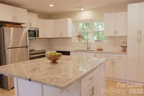 a kitchen with stainless steel appliances granite countertop a sink window and white cabinets