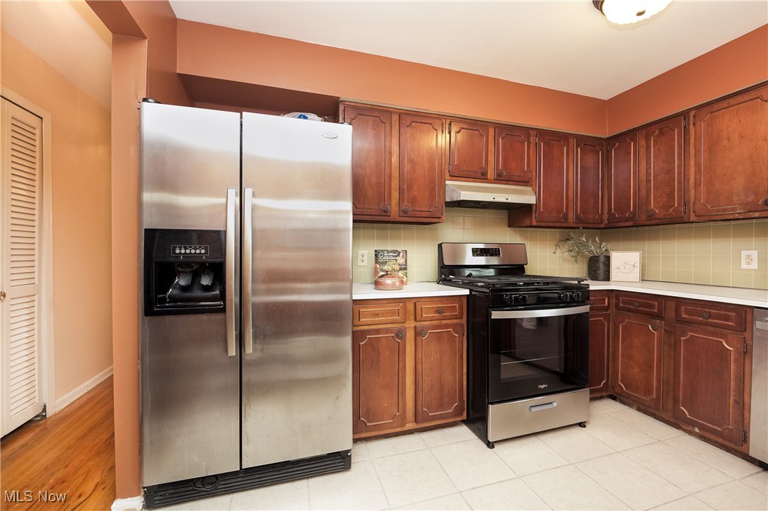 2674 Smith Road Fairlawn, OH 44333 - Photo 13 of 31 Kitchen with under cabinet range hood, baseboards, light countertops, appliances with stainless steel finishes, and decorative backsplash