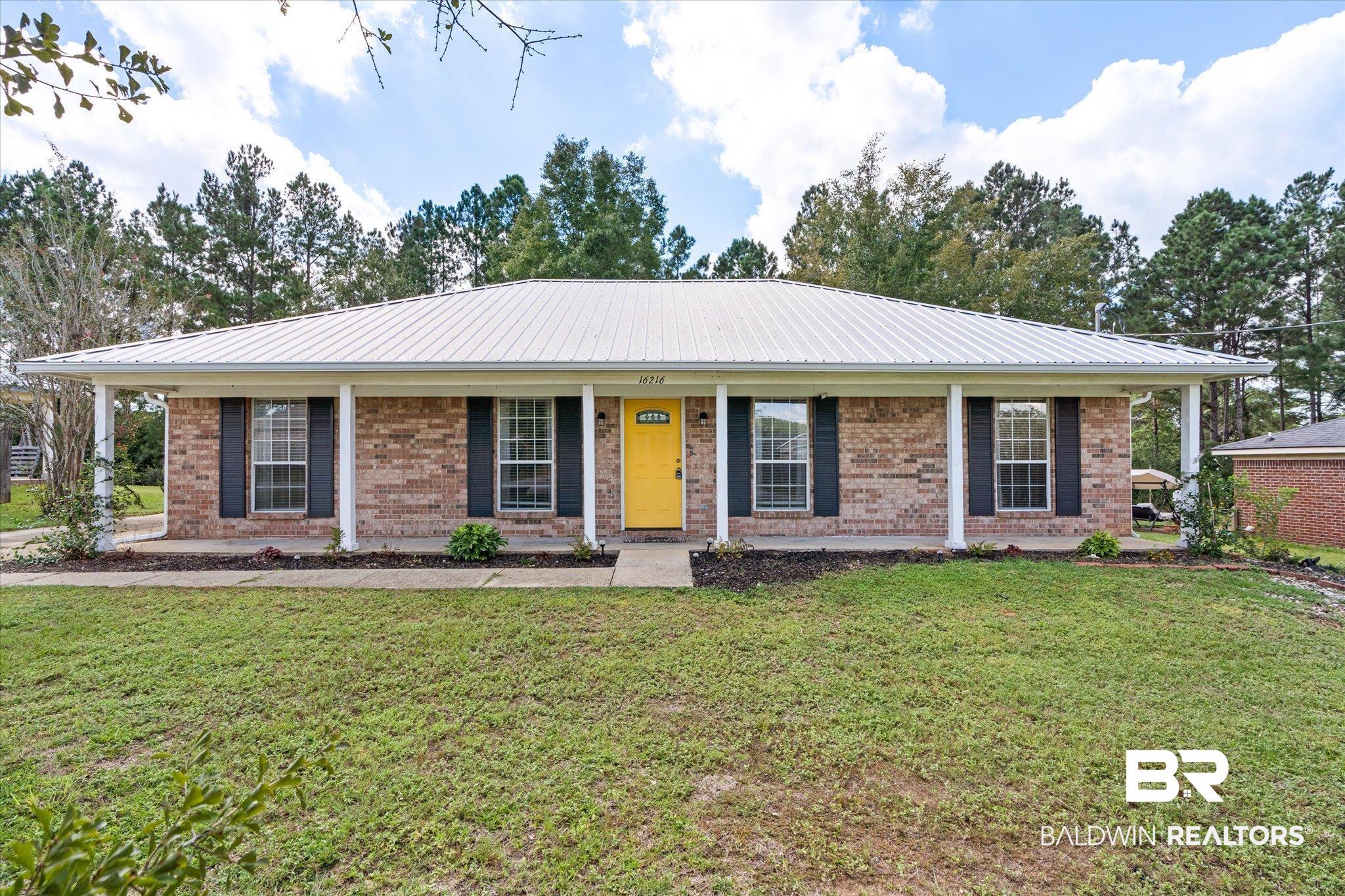 16216 Pointer Drive Foley, AL 36535 - Photo 1 of 21 Brick exterior with a metal roof, yellow front door, and covered front porch with white columns