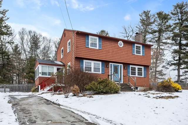 a front view of a house with a yard covered with snow and trees