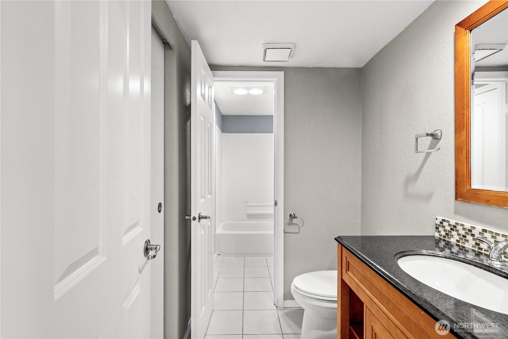 1321 South Puget Drive, Unit E15 Renton, WA 98055 - Photo 20 of 30 a bathroom with a granite countertop toilet a sink and a mirror