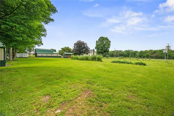 a backyard of a house with lots of green space and lake view in back