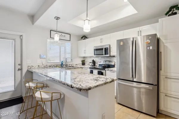 a kitchen with stainless steel appliances granite countertop a refrigerator a stove a sink a dining table and chairs