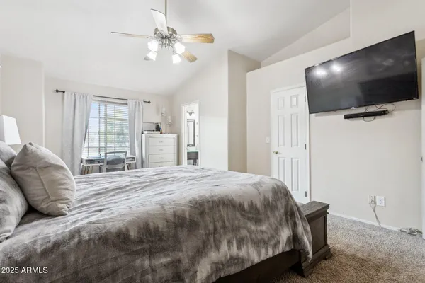a spacious bedroom with a bed and a flat screen tv
