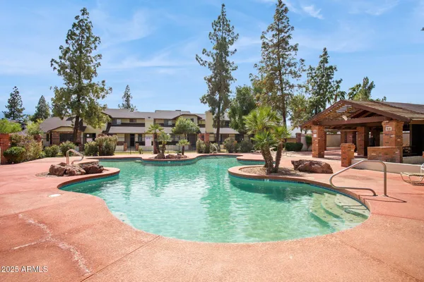 a view of a swimming pool with lawn chairs under an umbrella