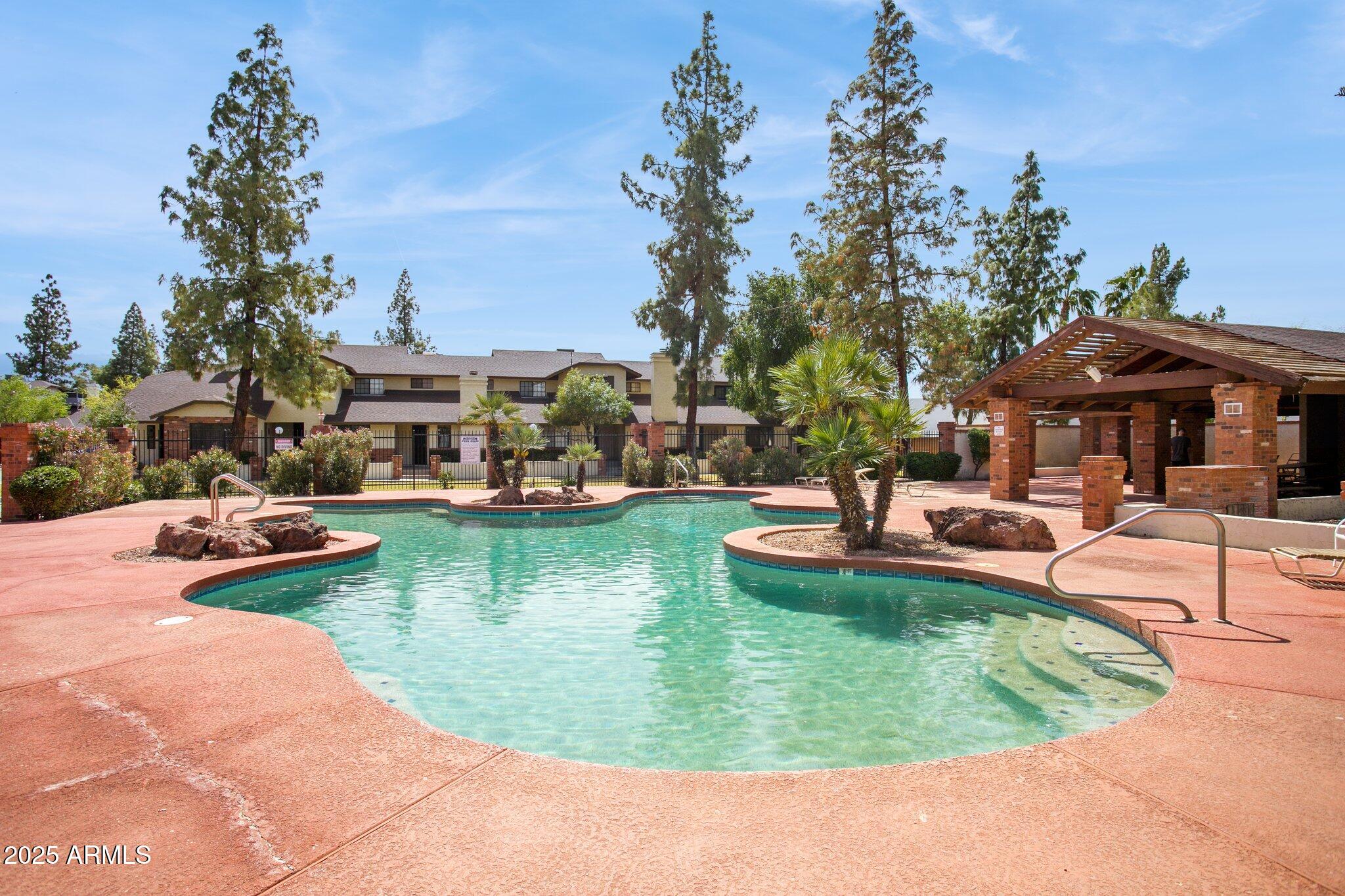170 East Guadalupe Road, Unit 152 Gilbert, AZ 85234 - Photo 6 of 29 a view of a swimming pool with lawn chairs under an umbrella