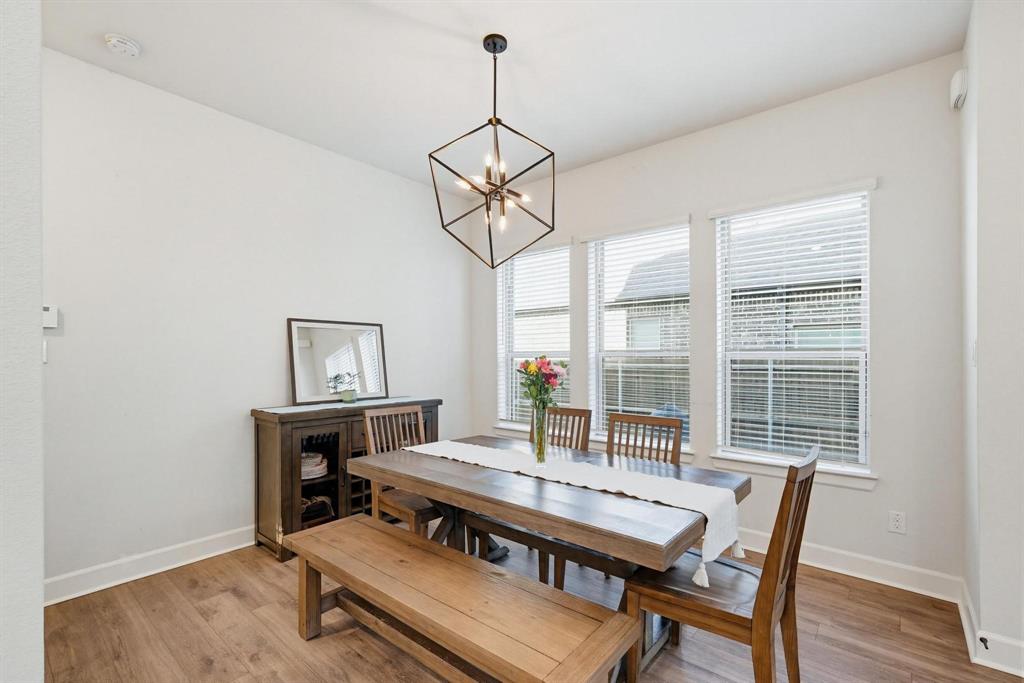 9341 Loggerhead Way Fort Worth, TX 76118 - Photo 17 of 35 Dining area featuring wood-finish flooring, white walls, and a contemporary geometric chandelier
