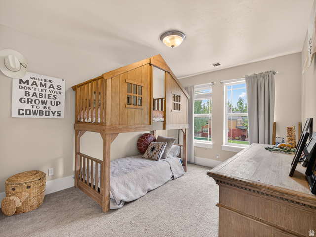 557 Craftsman Way Midway, UT 84049 - Photo 39 of 59 Well-lit room featuring a custom-built wood bed frame, neutral-toned wall paint, and light-colored carpet flooring