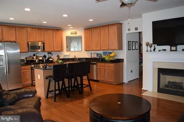 a kitchen with stainless steel appliances granite countertop a stove a sink a microwave a refrigerator and a island