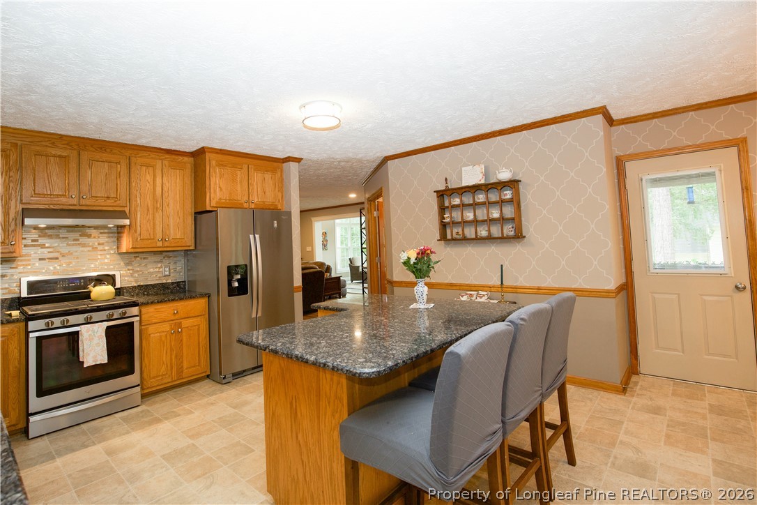 7815 Shuttle Road Fayetteville, NC 28311 - Photo 18 of 50 a kitchen with stainless steel appliances granite countertop a stove a refrigerator a kitchen island a table and chairs