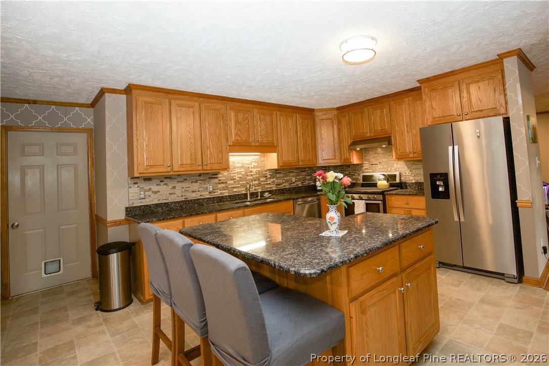 7815 Shuttle Road Fayetteville, NC 28311 - Photo 19 of 50 a kitchen with granite countertop a sink a center island stainless steel appliances and cabinets