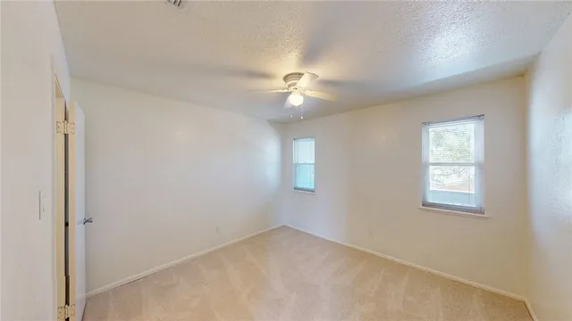 an empty room with windows and fan
