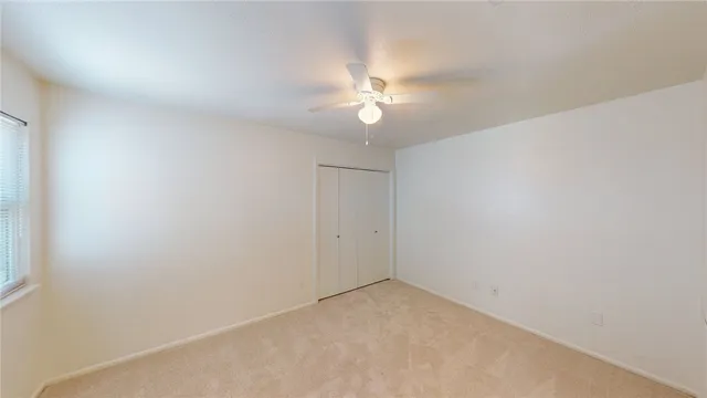 an empty room with a fan & a window