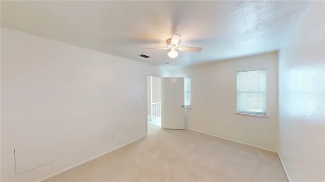 an empty room with a window and a fan