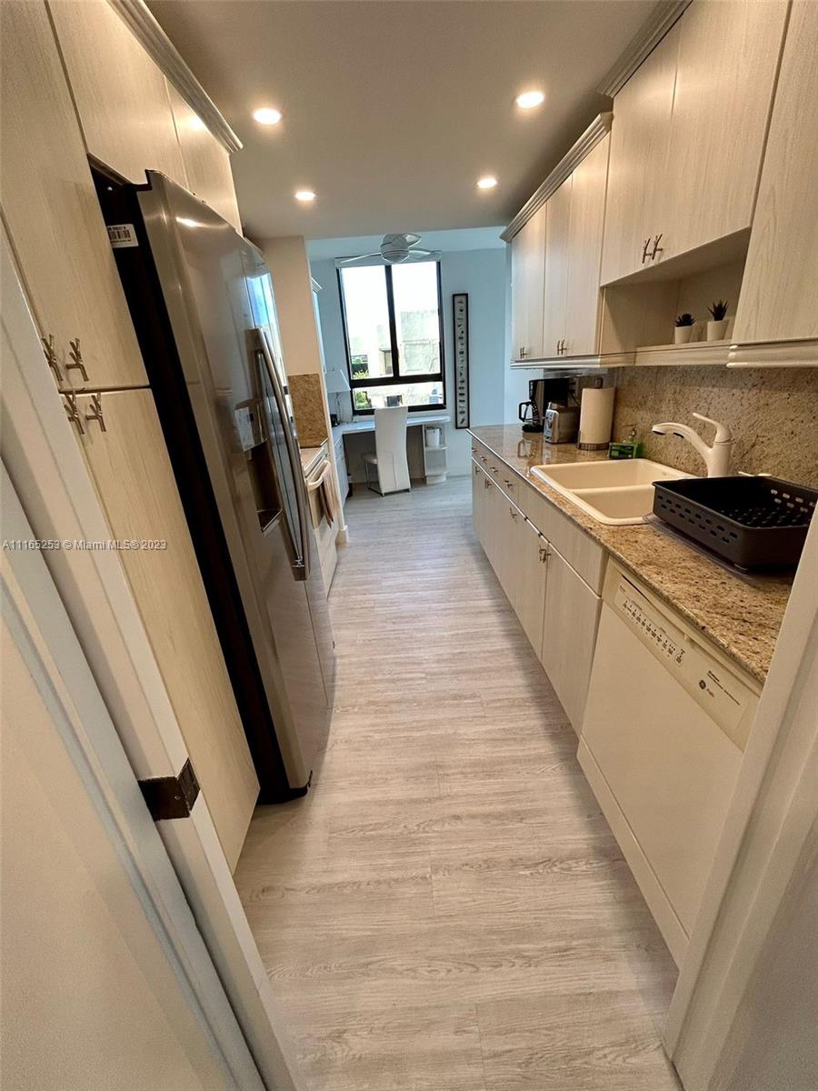 101 Crandon Boulevard, Unit 473 Key Biscayne, FL 33149 - Photo 23 of 24 a kitchen with stainless steel appliances a refrigerator a sink dishwasher a stove and a microwave oven with wooden floor