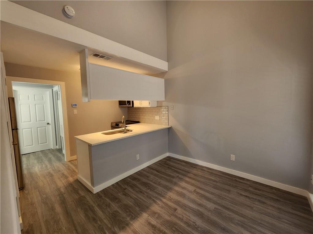 2815 Rio Grande Street, Unit 215 Austin, TX 78705 - Photo 2 of 11 A streamlined kitchen flows into an open concept dining area, featuring robust wood flooring.