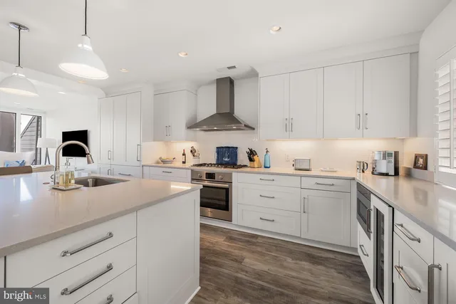 a kitchen with stainless steel appliances granite countertop a sink dishwasher a stove and white cabinets with wooden floor