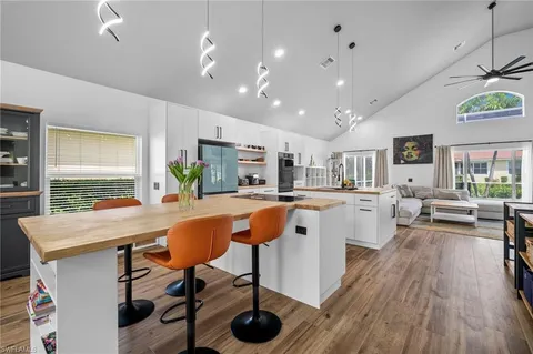 a living room with stainless steel appliances kitchen island granite countertop furniture and a wooden floor