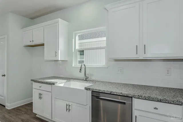 a kitchen with granite countertop white cabinets and a sink