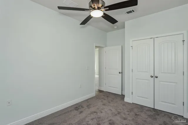 a view of an empty room and chandelier fan