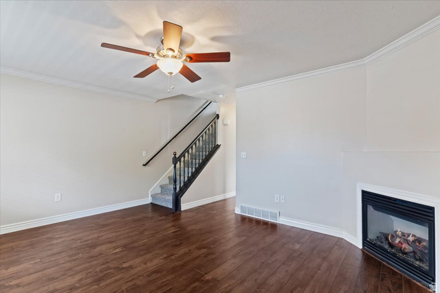 2350 South Highway 89, Unit 4 Perry, UT 84302 - Photo 4 of 30 Unfurnished living room featuring a glass covered fireplace, ornamental molding, dark wood-type flooring, and a ceiling fan