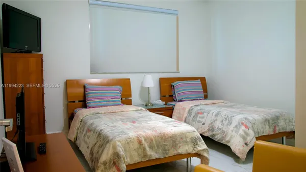 a bedroom with two beds and a flat screen tv
