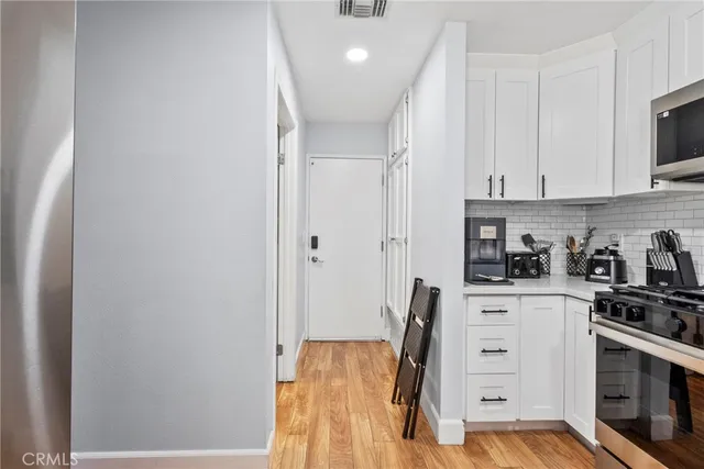 a kitchen with stainless steel appliances a stove a sink and white cabinets
