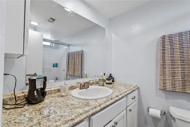 a bathroom with a granite countertop sink a toilet and a mirror