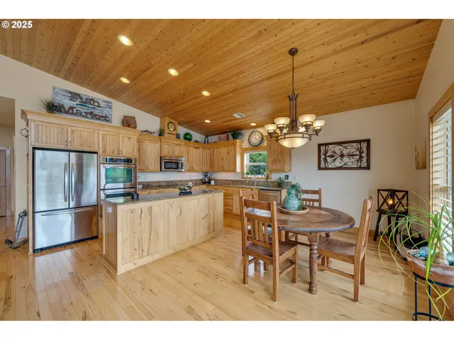 a kitchen with stainless steel appliances kitchen island granite countertop a table and chairs in it