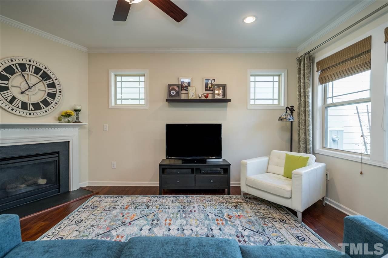 5630 Wade Park Boulevard Raleigh, NC 27607 - Photo 11 of 30 Living room features a gas fireplace, windows on both walls, hardwoods, fan, and recessed lighting!