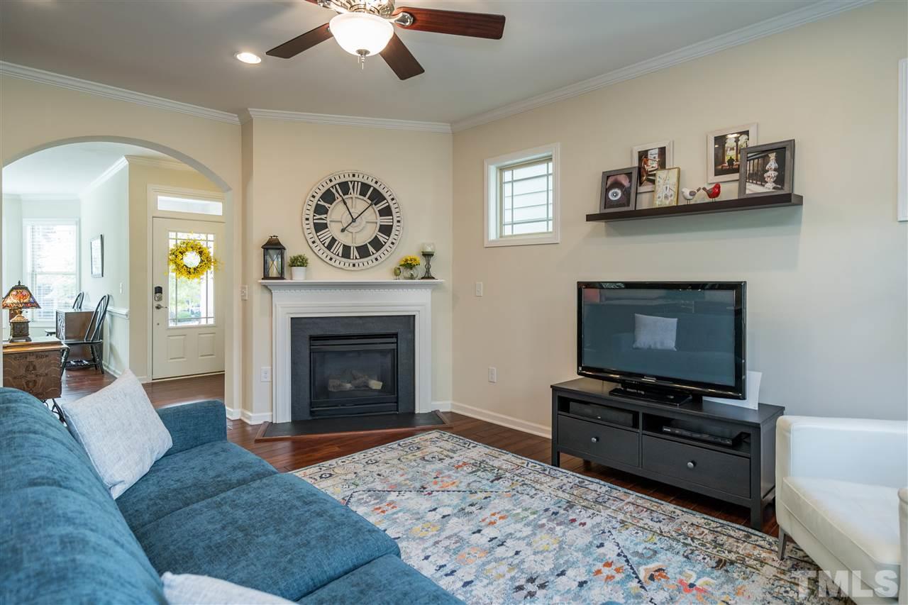 5630 Wade Park Boulevard Raleigh, NC 27607 - Photo 12 of 30 Living room features a gas fireplace, windows on both walls, hardwoods, fan, and recessed lighting!