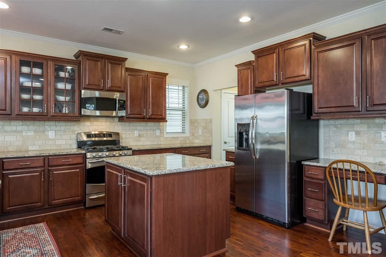 5630 Wade Park Boulevard Raleigh, NC 27607 - Photo 7 of 30 This kitchen has it all! Open concept, island, working desk, granite, subway tile, stainless appliances, included refrigerator, glass front cabinet and recessed can lighting!