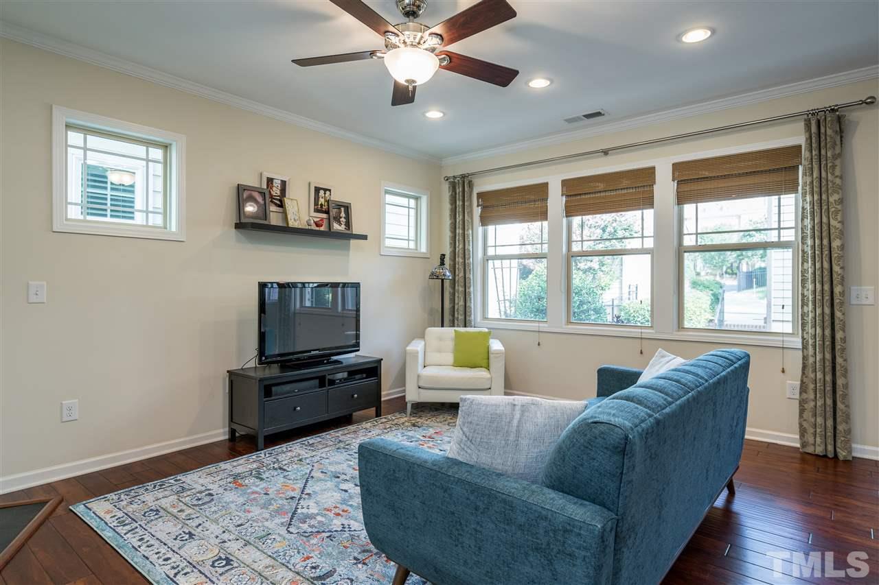 5630 Wade Park Boulevard Raleigh, NC 27607 - Photo 10 of 30 Living room features a gas fireplace, windows on both walls, hardwoods, fan, and recessed lighting!
