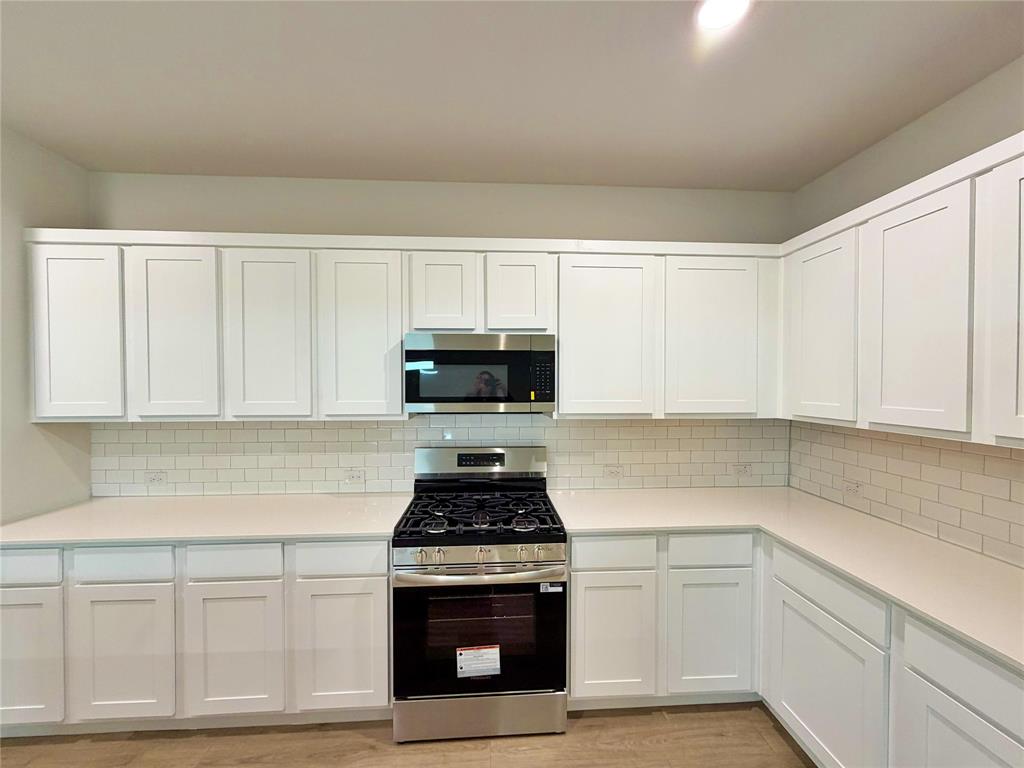 2203 Heatwave Lane Princeton, TX 75407 - Photo 6 of 32 a kitchen with white cabinets and appliances