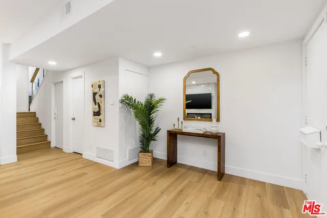 a view of a hallway to room with wooden floor and potted plant