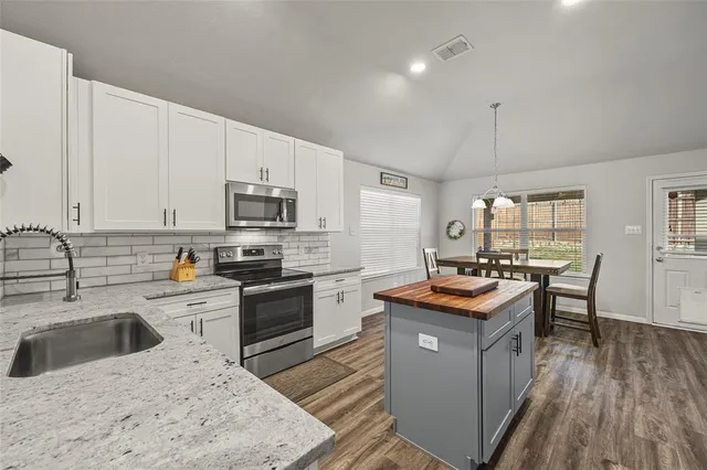 a kitchen with granite countertop stainless steel appliances a stove sink microwave and cabinets