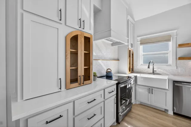 a kitchen with stainless steel appliances granite countertop a sink a stove and a window