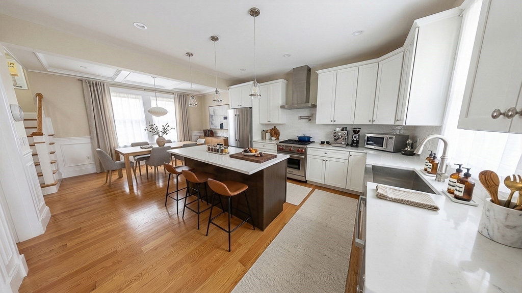 42 Parsons Street Newton, MA 02465 - Photo 7 of 36 a open kitchen with stainless steel appliances granite countertop a stove a refrigerator a sink a dining table and chairs with wooden floor