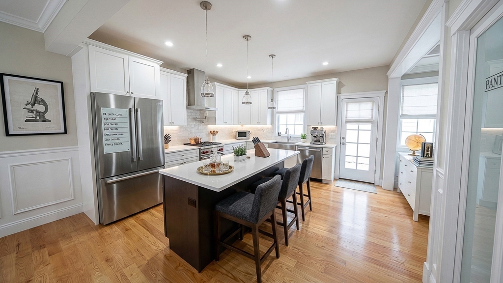 42 Parsons Street Newton, MA 02465 - Photo 10 of 36 a kitchen with stainless steel appliances granite countertop a refrigerator a sink dishwasher a stove and a dining table with wooden floor