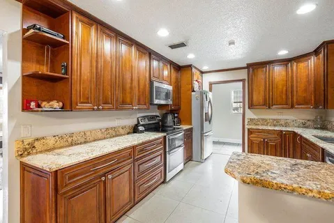 a view of a kitchen with kitchen island stainless steel appliances refrigerator stove microwave and cabinets