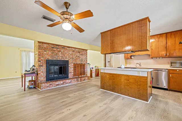 a kitchen with stainless steel appliances a stove top oven a sink cabinets and a fireplace