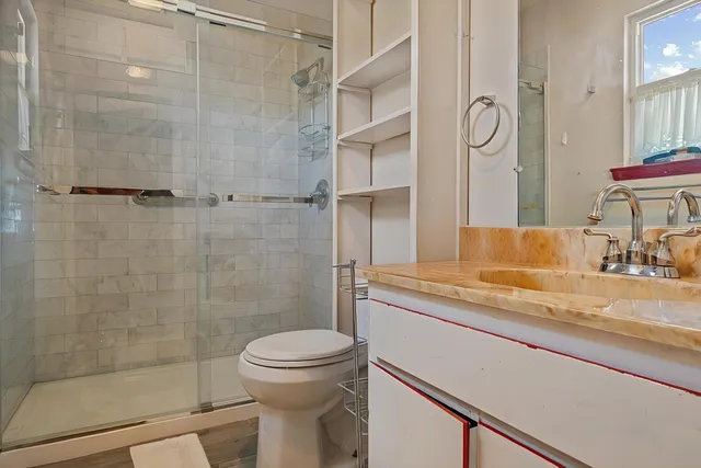 a bathroom with a granite countertop sink a toilet and shower