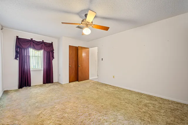a view of a livingroom with a chandelier fan and a window