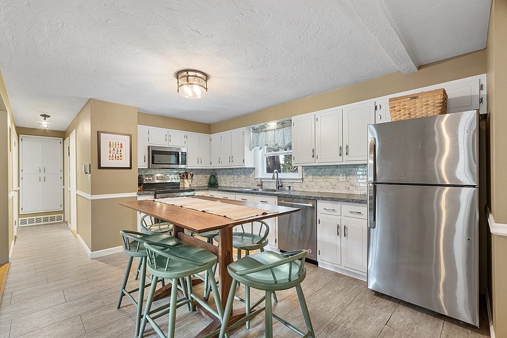 10 Truro Street Worcester, MA 01603 - Photo 5 of 32 a kitchen with stainless steel appliances a refrigerator a stove a sink a dining table and chairs
