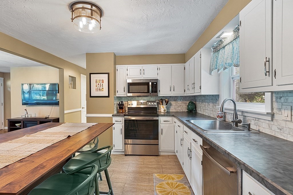 10 Truro Street Worcester, MA 01603 - Photo 6 of 32 a kitchen with stainless steel appliances granite countertop a stove a sink dishwasher and a microwave oven with white cabinets