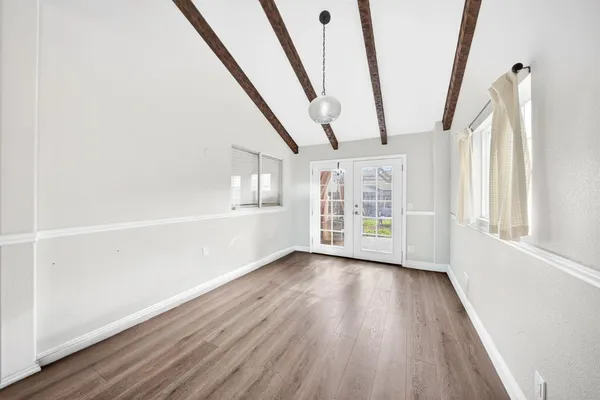 a view of an empty room with wooden floor and windows