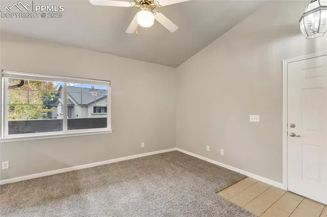 an empty room with a chandelier fan and windows